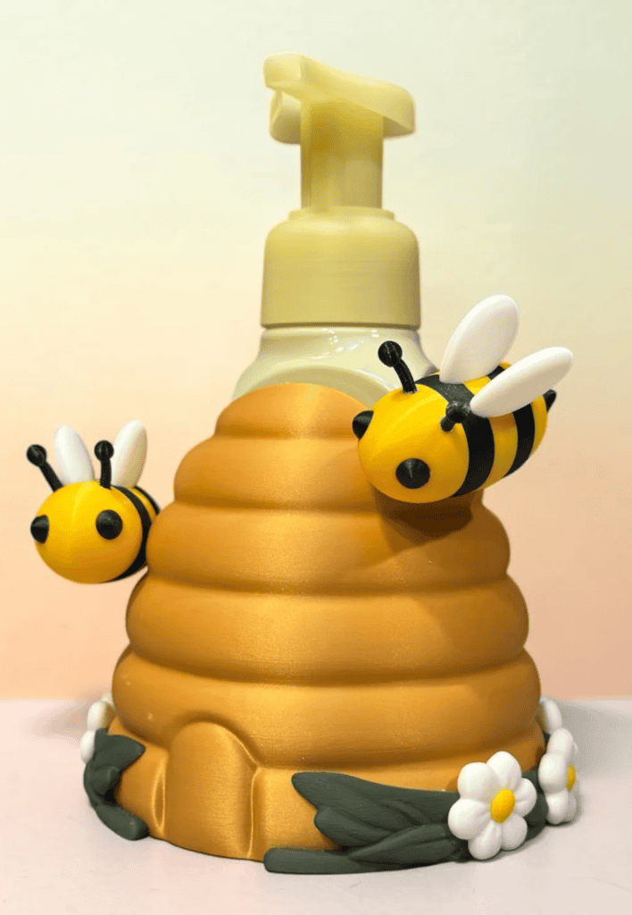 Bee hive-shaped soap dispenser with bee and flower decorations. Acadiana3DPrints