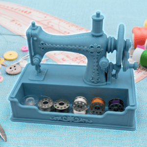 Blue miniature sewing machine with colorful thread spools and sewing tools. Acadiana3DPrints