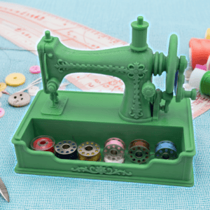 Green miniature sewing machine with colorful thread spools and sewing tools. Acadiana3DPrints