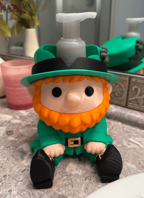 Cute leprechaun soap dispenser with orange beard and green outfit on bathroom counter. Acadiana3DPrints