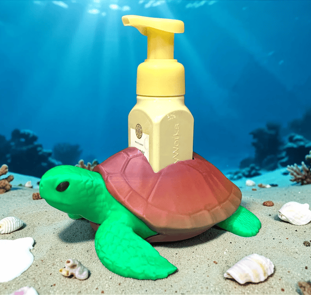 Sea turtle-shaped hand sanitizer dispenser on ocean-themed background. Acadiana3DPrints